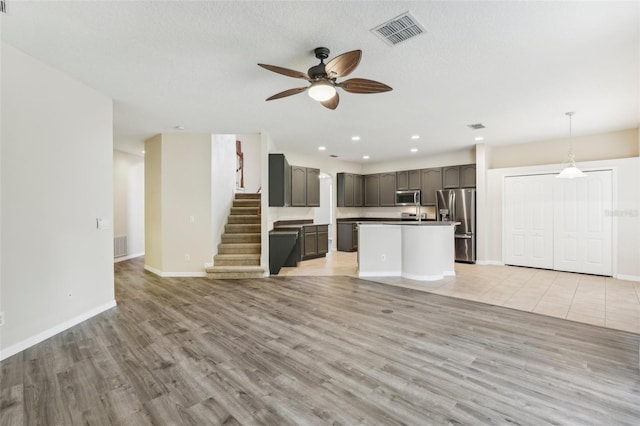 unfurnished living room featuring ceiling fan, a textured ceiling, and light hardwood / wood-style flooring