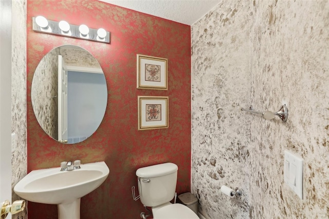 bathroom featuring a textured ceiling, toilet, and sink