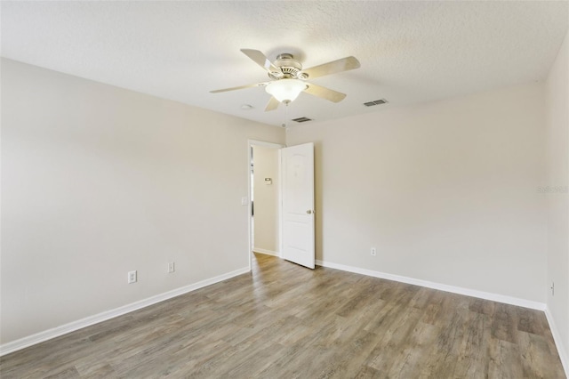 empty room with ceiling fan, wood-type flooring, and a textured ceiling