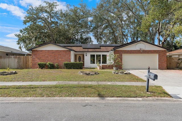 ranch-style house with a front yard, solar panels, and a garage