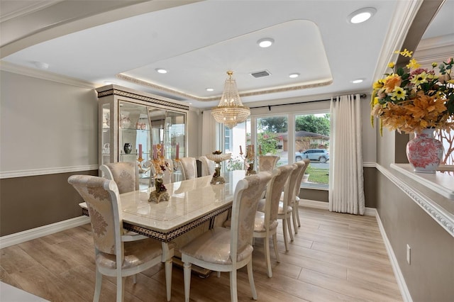 dining area featuring light wood-style flooring, visible vents, baseboards, a tray ceiling, and crown molding