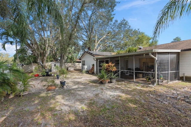 back of house featuring an outdoor structure, fence, a sunroom, and roof mounted solar panels