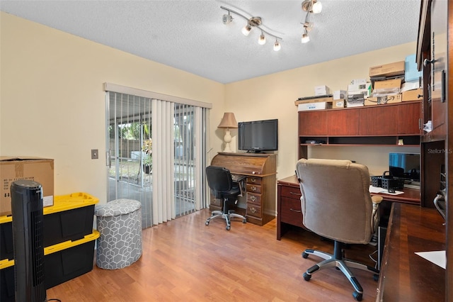 home office with light wood-type flooring and a textured ceiling