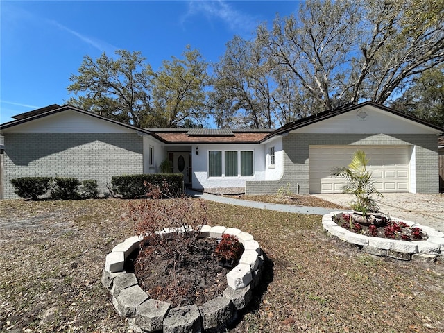 single story home featuring roof mounted solar panels, brick siding, and an attached garage