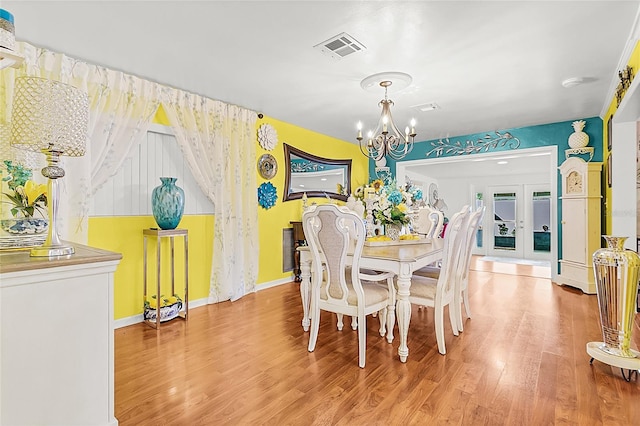 dining space with wood-type flooring, a notable chandelier, and french doors