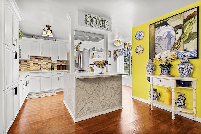 kitchen with white cabinetry, hardwood / wood-style floors, a center island, and tasteful backsplash