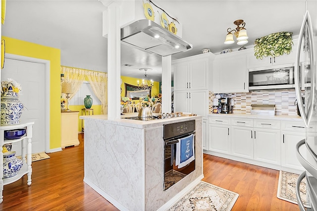 kitchen with appliances with stainless steel finishes, backsplash, ventilation hood, white cabinets, and light wood-type flooring