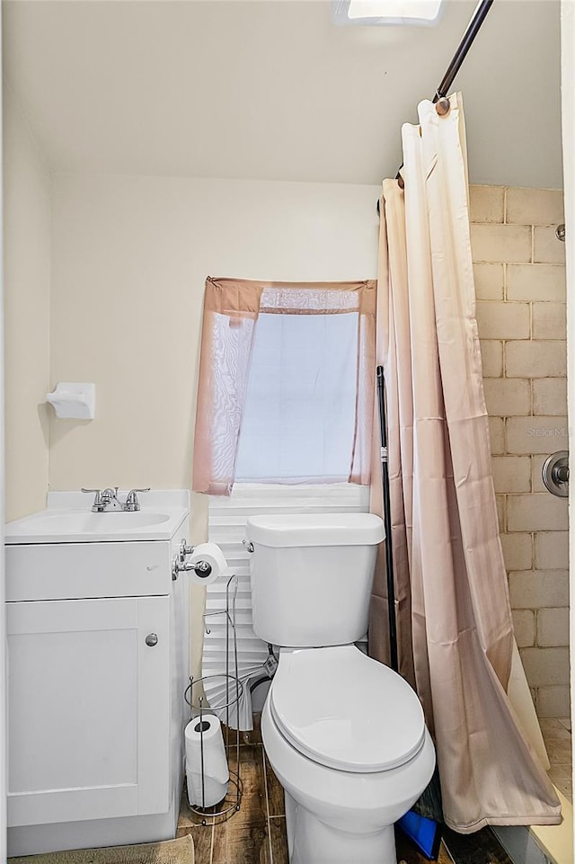 bathroom with walk in shower, hardwood / wood-style floors, vanity, and toilet