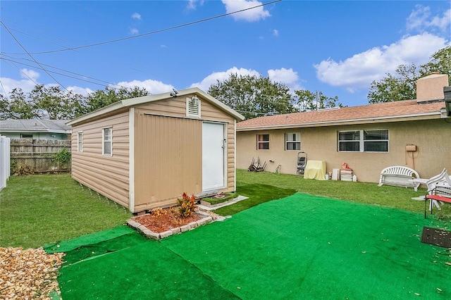 rear view of property with a yard and a storage unit