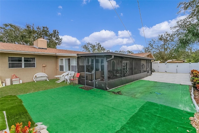 back of property featuring fence, a sunroom, stucco siding, a chimney, and a patio area