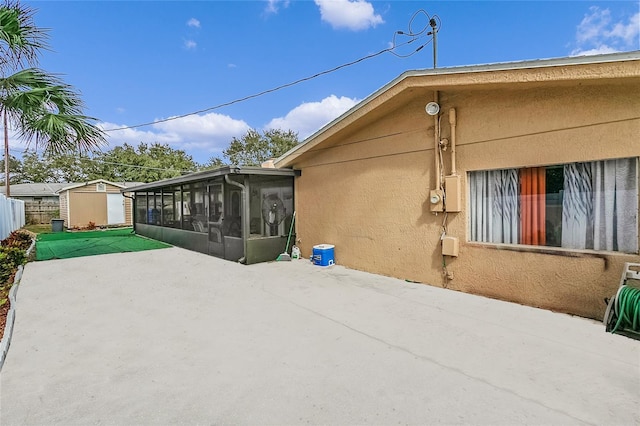 rear view of house featuring an outbuilding, a storage unit, a sunroom, a patio area, and fence