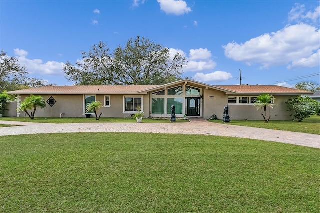 view of front of house with decorative driveway, a front yard, and stucco siding