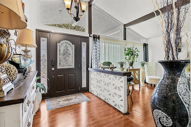 foyer featuring vaulted ceiling with beams, an inviting chandelier, and wood finished floors