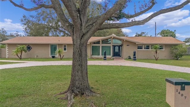 view of front of house featuring driveway, a front lawn, and stucco siding