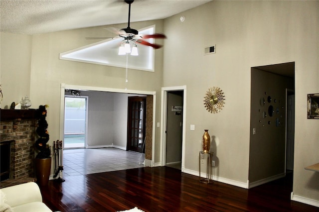 living room with a fireplace, a textured ceiling, high vaulted ceiling, hardwood / wood-style floors, and ceiling fan