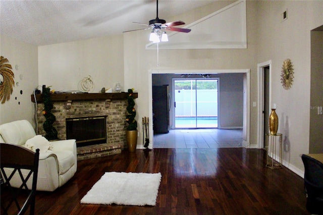 living room with a fireplace, dark hardwood / wood-style flooring, ceiling fan, and vaulted ceiling