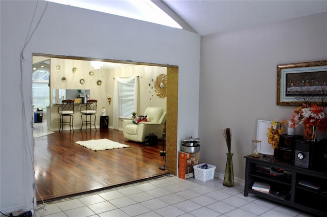 interior space featuring lofted ceiling, a textured ceiling, and light hardwood / wood-style flooring