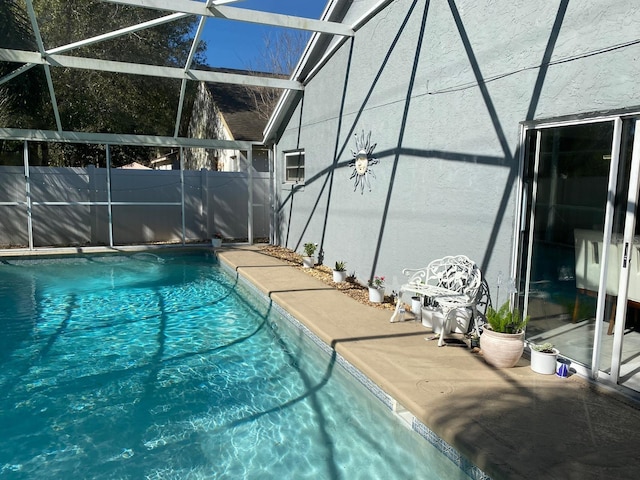 view of swimming pool featuring glass enclosure and a patio area