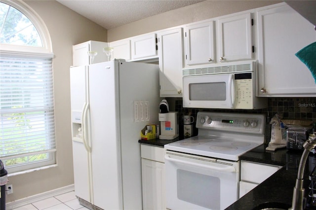 kitchen with tasteful backsplash, a textured ceiling, light tile patterned floors, white appliances, and white cabinets