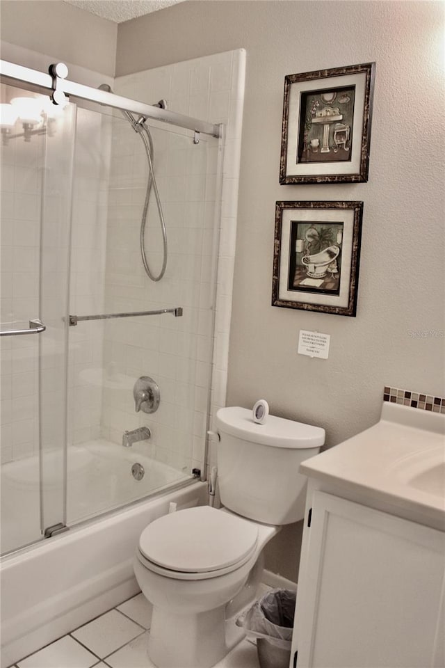 full bathroom with bath / shower combo with glass door, tile patterned flooring, vanity, and toilet