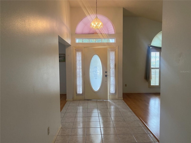 tiled foyer entrance with a chandelier and a high ceiling