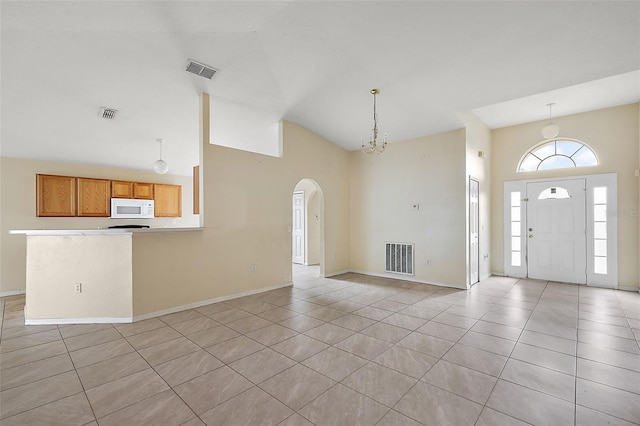 entryway featuring light tile patterned flooring, high vaulted ceiling, and a notable chandelier