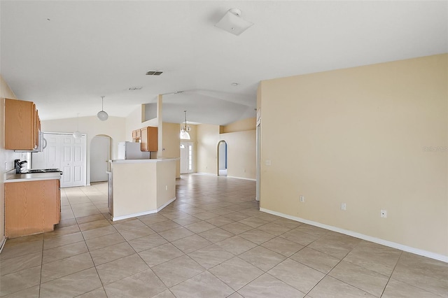 kitchen featuring a kitchen island, white refrigerator, light tile patterned floors, pendant lighting, and lofted ceiling