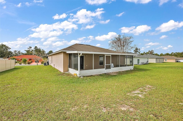 rear view of property featuring a sunroom and a lawn