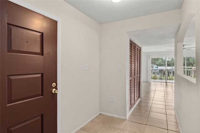 corridor with a textured ceiling and light tile patterned floors