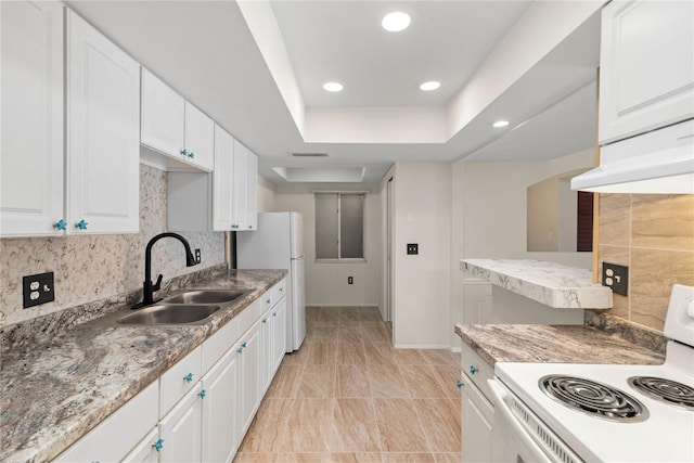 kitchen featuring white cabinets, sink, tasteful backsplash, a raised ceiling, and white appliances