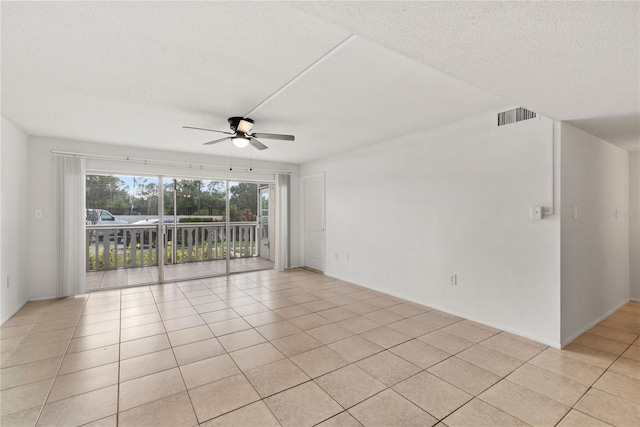 empty room with a textured ceiling, light tile patterned floors, and ceiling fan