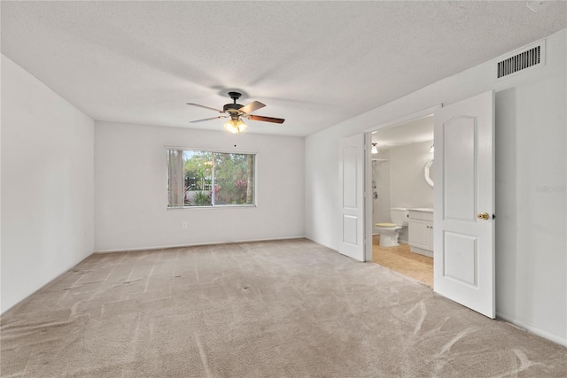 empty room featuring a textured ceiling, light carpet, and ceiling fan