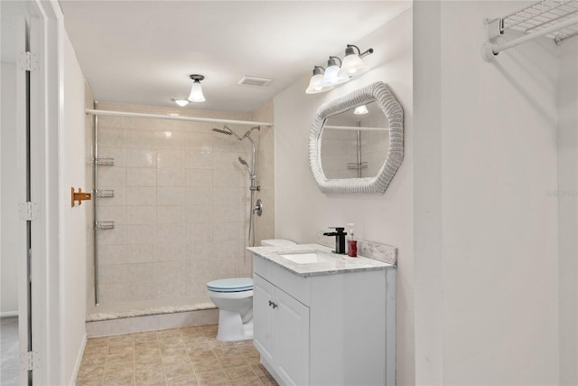 bathroom featuring tiled shower, toilet, and vanity