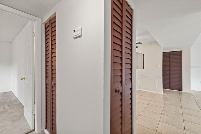 corridor with a textured ceiling and light tile patterned flooring