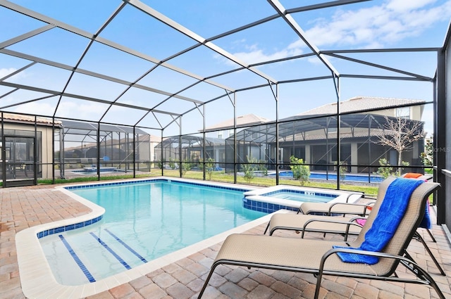 view of pool featuring glass enclosure, a patio, and an in ground hot tub