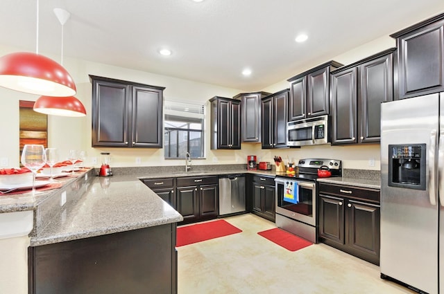 kitchen featuring light stone counters, appliances with stainless steel finishes, decorative light fixtures, sink, and kitchen peninsula