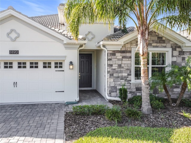 1490 Olympic Club Blvd, Champions Gate, FL 33896 - view of front of house featuring a tile roof, stone siding, a garage, stucco siding, and a chimney