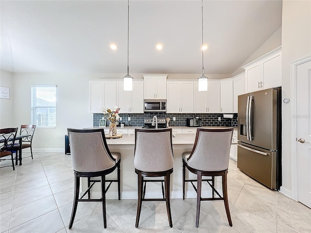 kitchen with stainless steel appliances, hanging light fixtures, white cabinetry, and vaulted ceiling