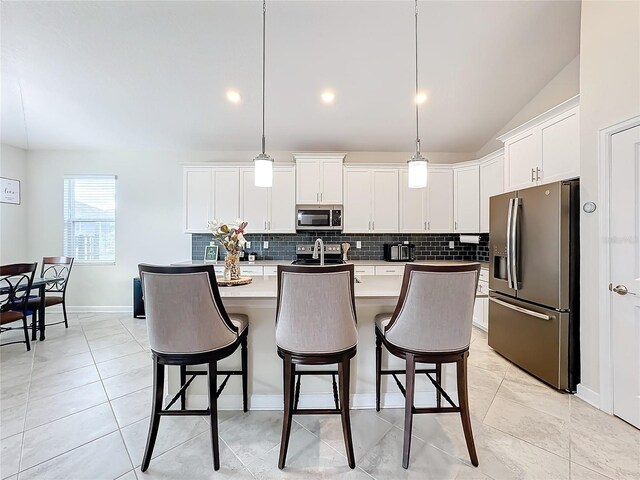 1490 Olympic Club Blvd, Champions Gate, FL 33896 - kitchen featuring stainless steel appliances, decorative backsplash, white cabinetry, a kitchen breakfast bar, and an island with sink