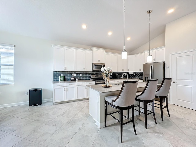 kitchen with stainless steel appliances, lofted ceiling, a center island with sink, pendant lighting, and white cabinetry