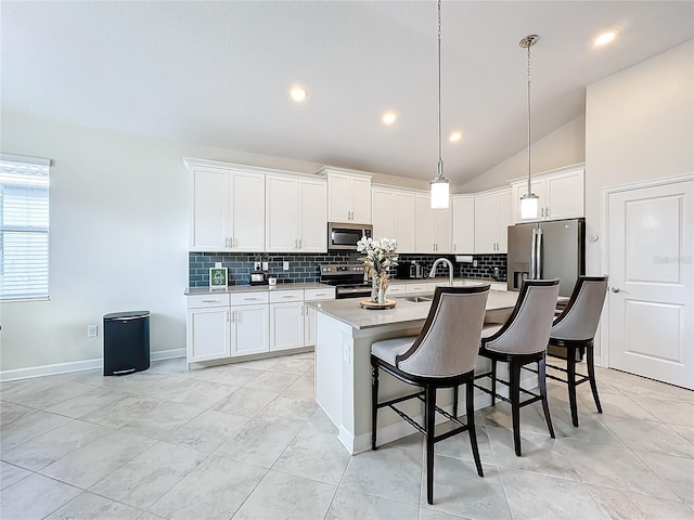 1490 Olympic Club Blvd, Champions Gate, FL 33896 - kitchen featuring appliances with stainless steel finishes, lofted ceiling, tasteful backsplash, a kitchen island with sink, and a breakfast bar area
