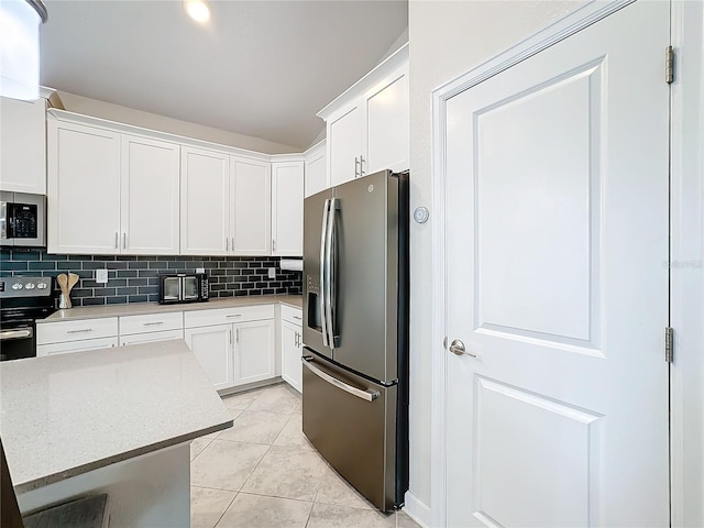 kitchen with stainless steel appliances, light tile patterned floors, backsplash, a kitchen island, and white cabinets