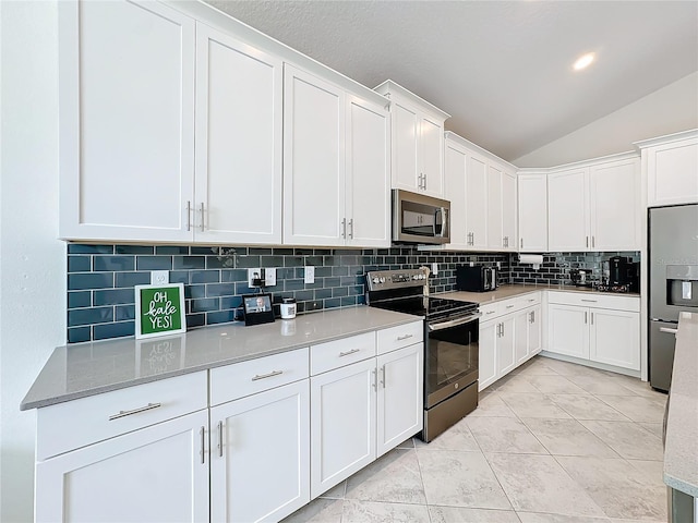 kitchen featuring decorative backsplash, appliances with stainless steel finishes, light tile patterned floors, white cabinets, and vaulted ceiling