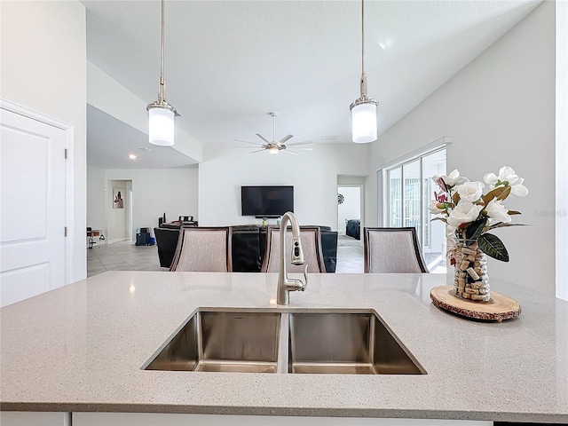 kitchen featuring pendant lighting, sink, light stone counters, and ceiling fan