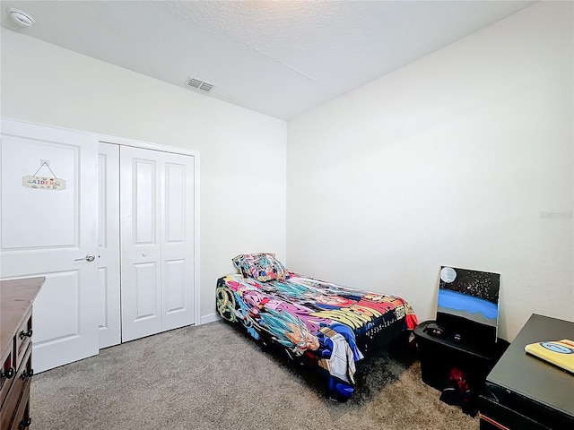 carpeted bedroom featuring a textured ceiling and a closet