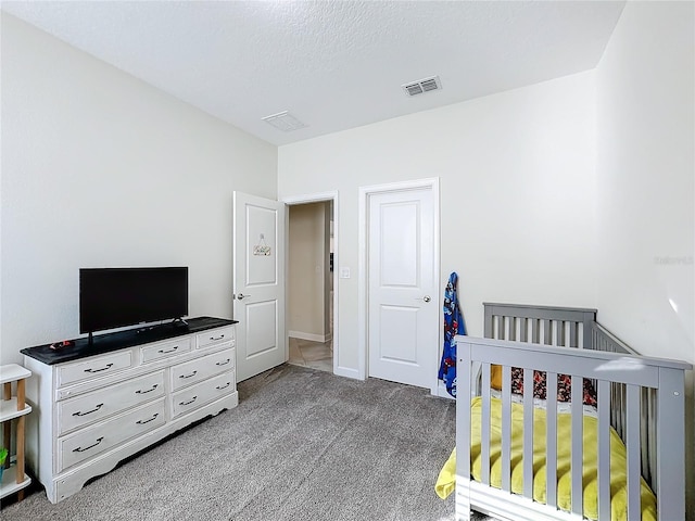 carpeted bedroom with a crib and a textured ceiling