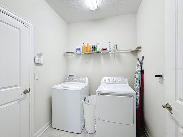 laundry room with light tile patterned floors, a textured ceiling, and washing machine and clothes dryer