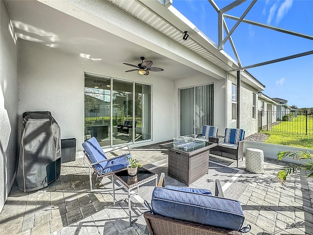 view of patio / terrace with ceiling fan, glass enclosure, and an outdoor living space with a fire pit