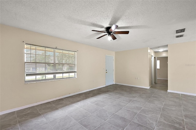 tiled empty room with ceiling fan and a textured ceiling