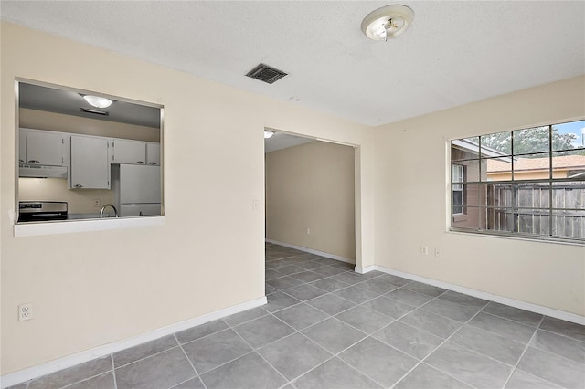 unfurnished room with tile patterned flooring and a textured ceiling